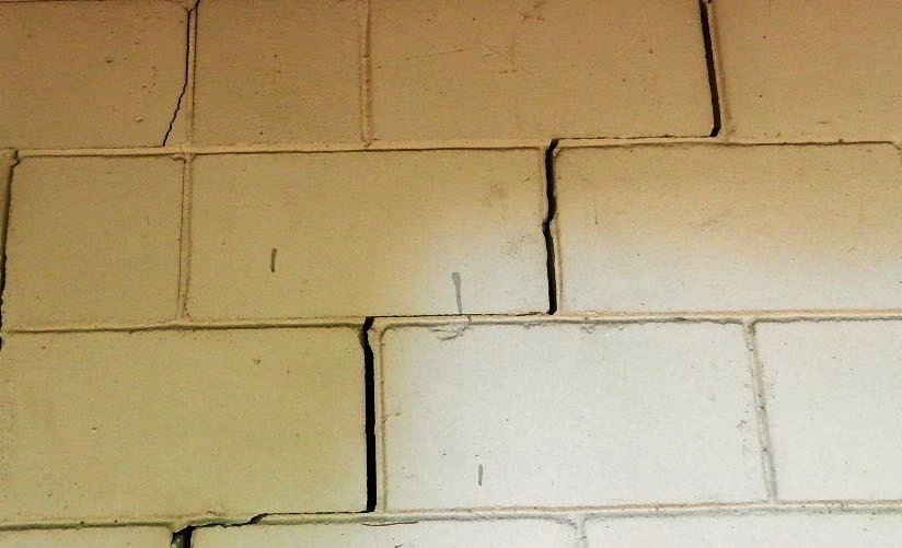 Fissure en escalier dans la maçonnerie d’une façade de maison.